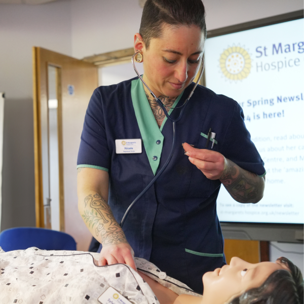 Female clinician listening to heartbeat on a mannequin.