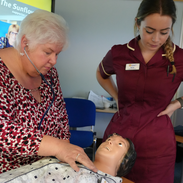two clinicians - one checking for a pulse on a mannequin