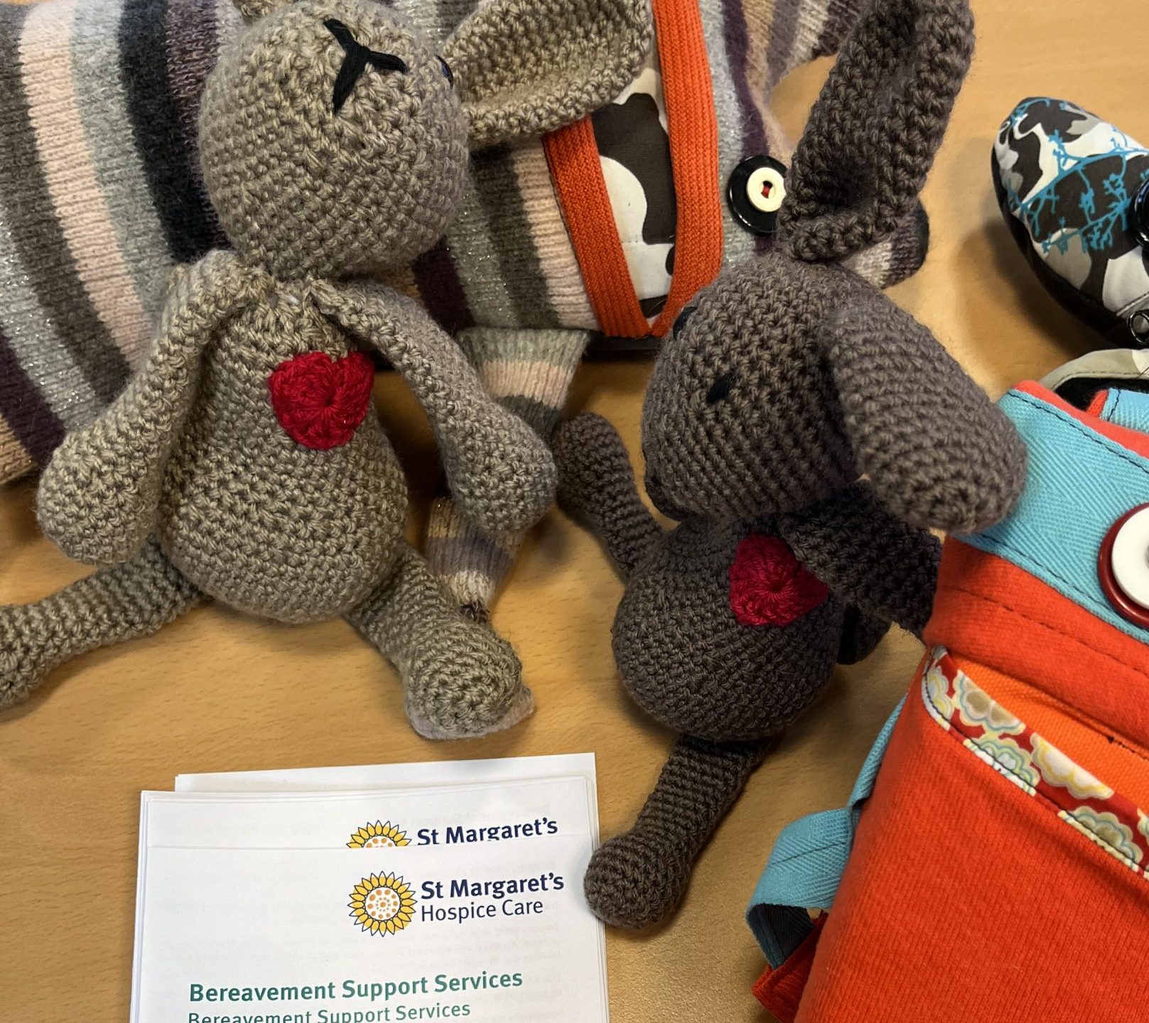 Knitted worry doll toys and a bereavement leaflet sat on a table