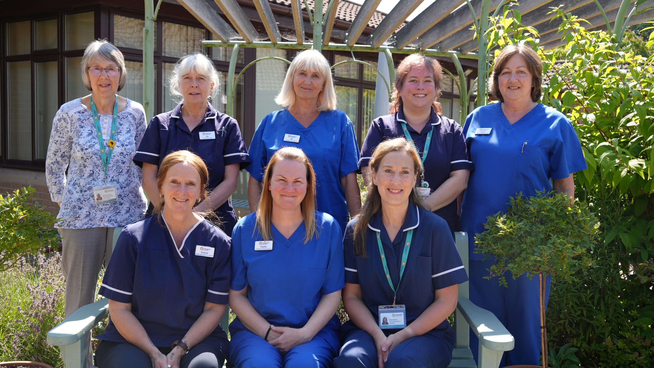 8 women in clinical uniform standing and sitting together outside