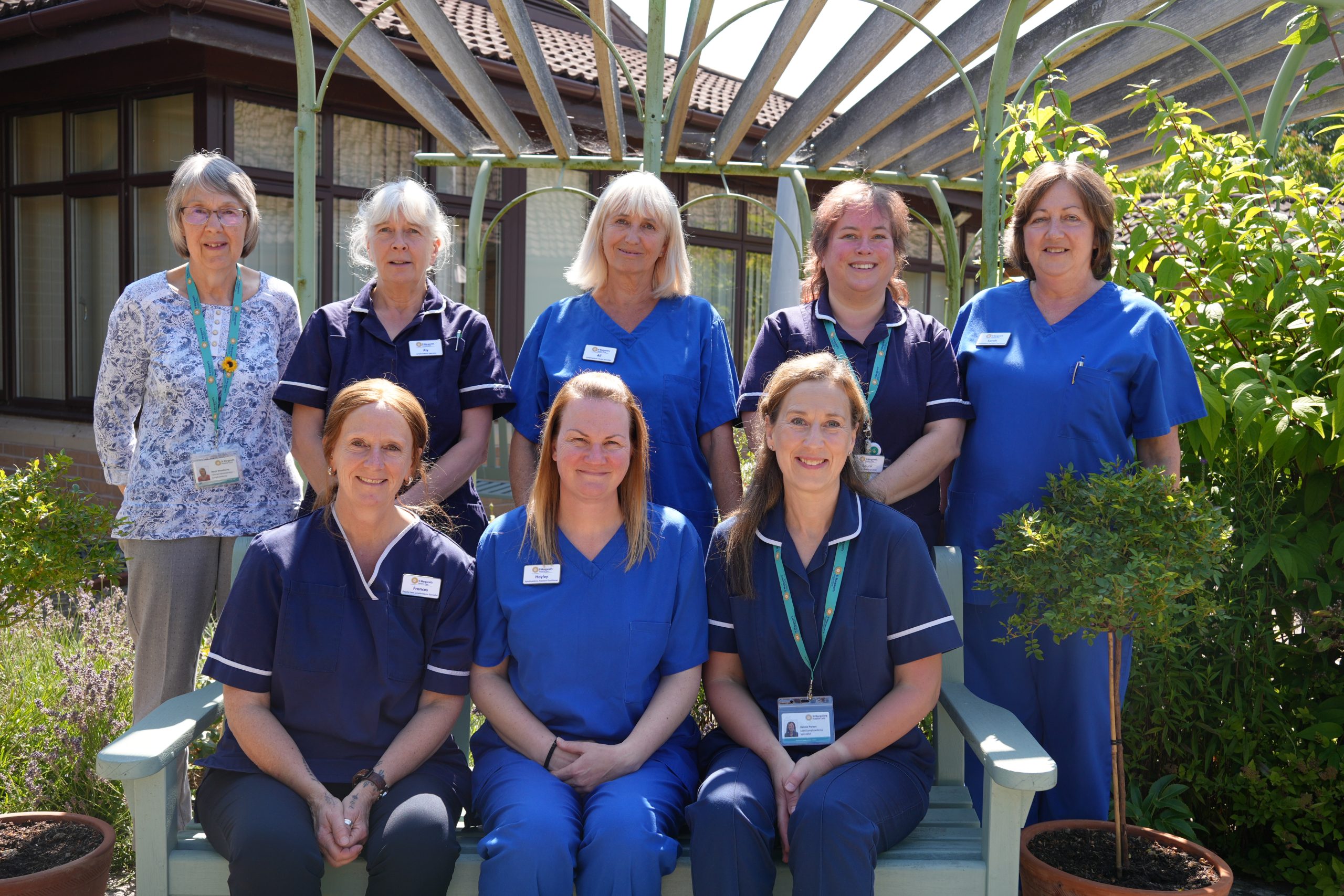 8 women in clinical uniform standing and sitting together outside
