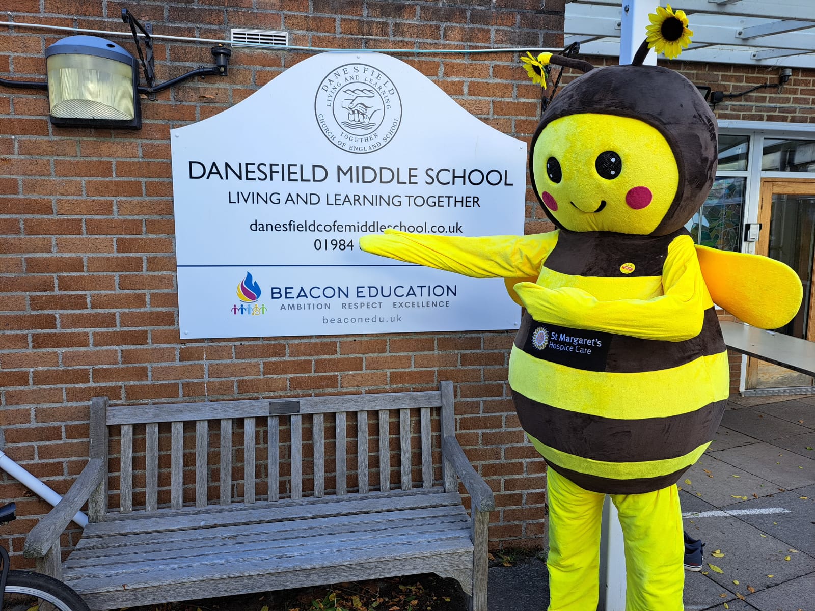 Bumblebee mascot stood by the wall of a primary school