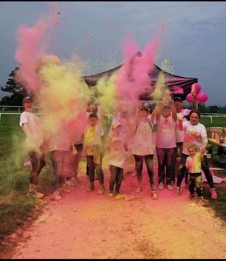 Group of volunteers throwing dry paint powder in the air