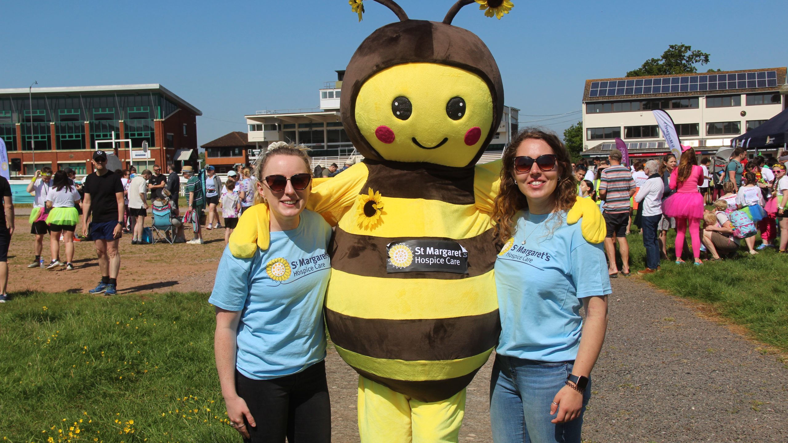 two female volunteers stood with a mascot bumble bee