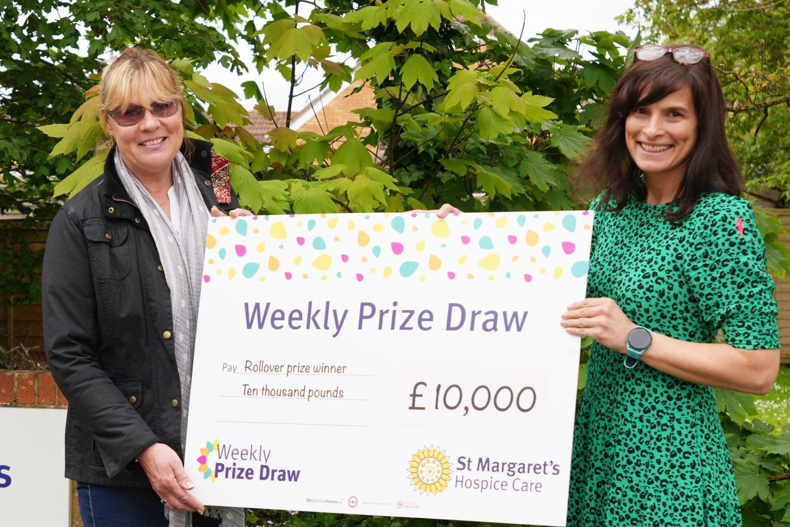 Female Weekly Prize draw winner with her £10,000 giant cheque presented by female staff member