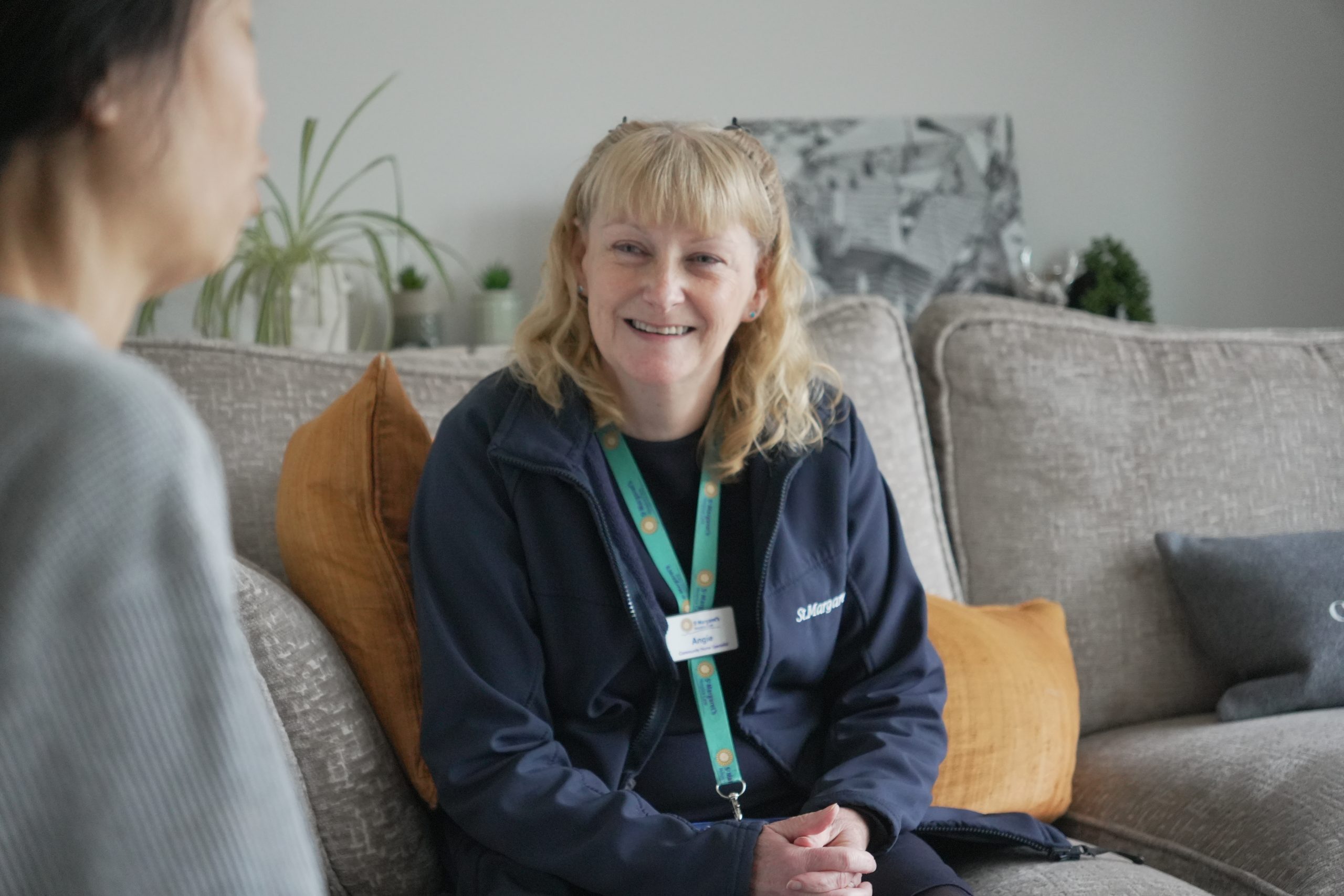 female nurse sat on a sofa in a patient's home