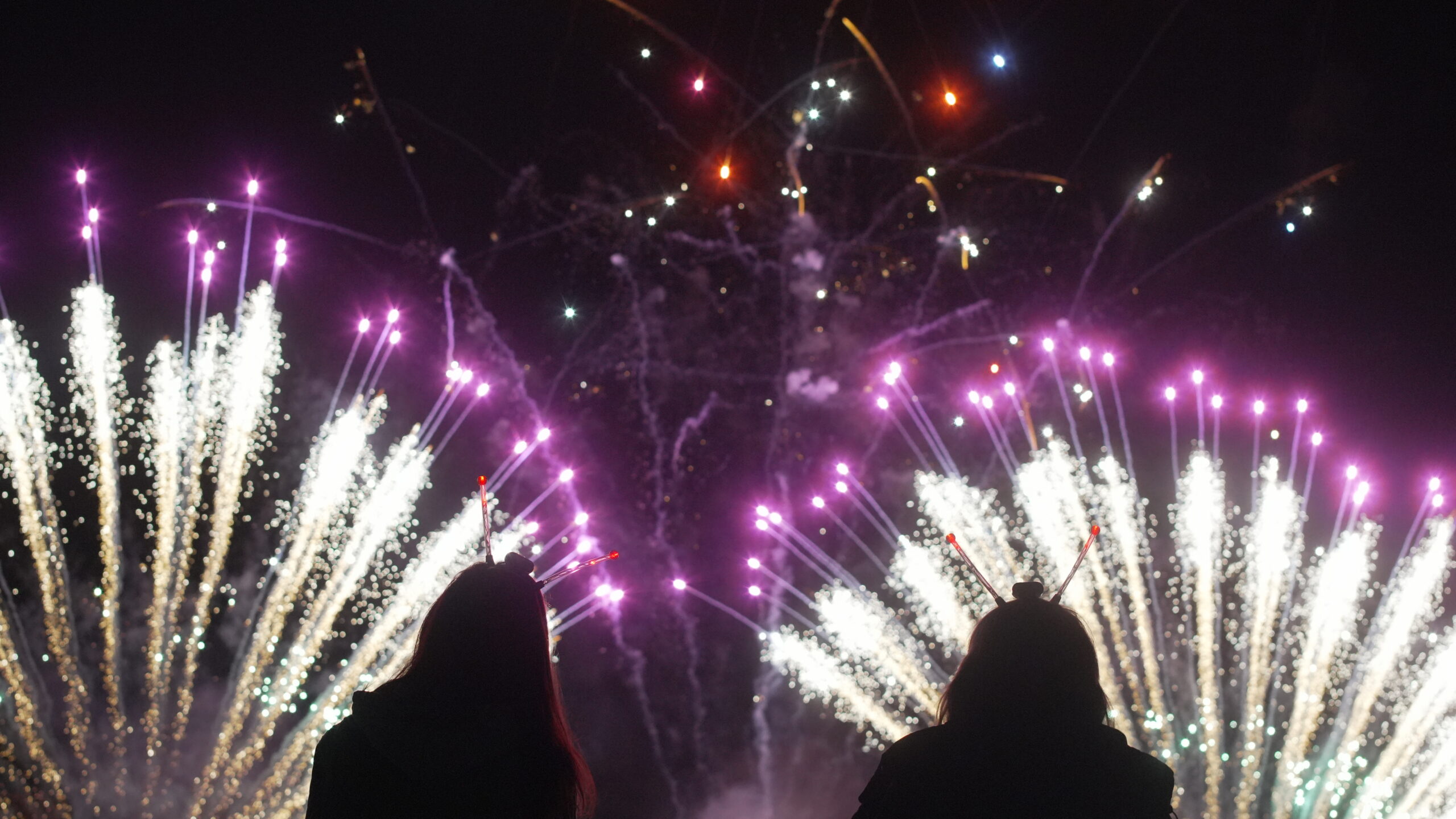 Silhouettes of people watching colourful fireworks bursting in the night sky at St Margaret’s Hospice Fireworks Night