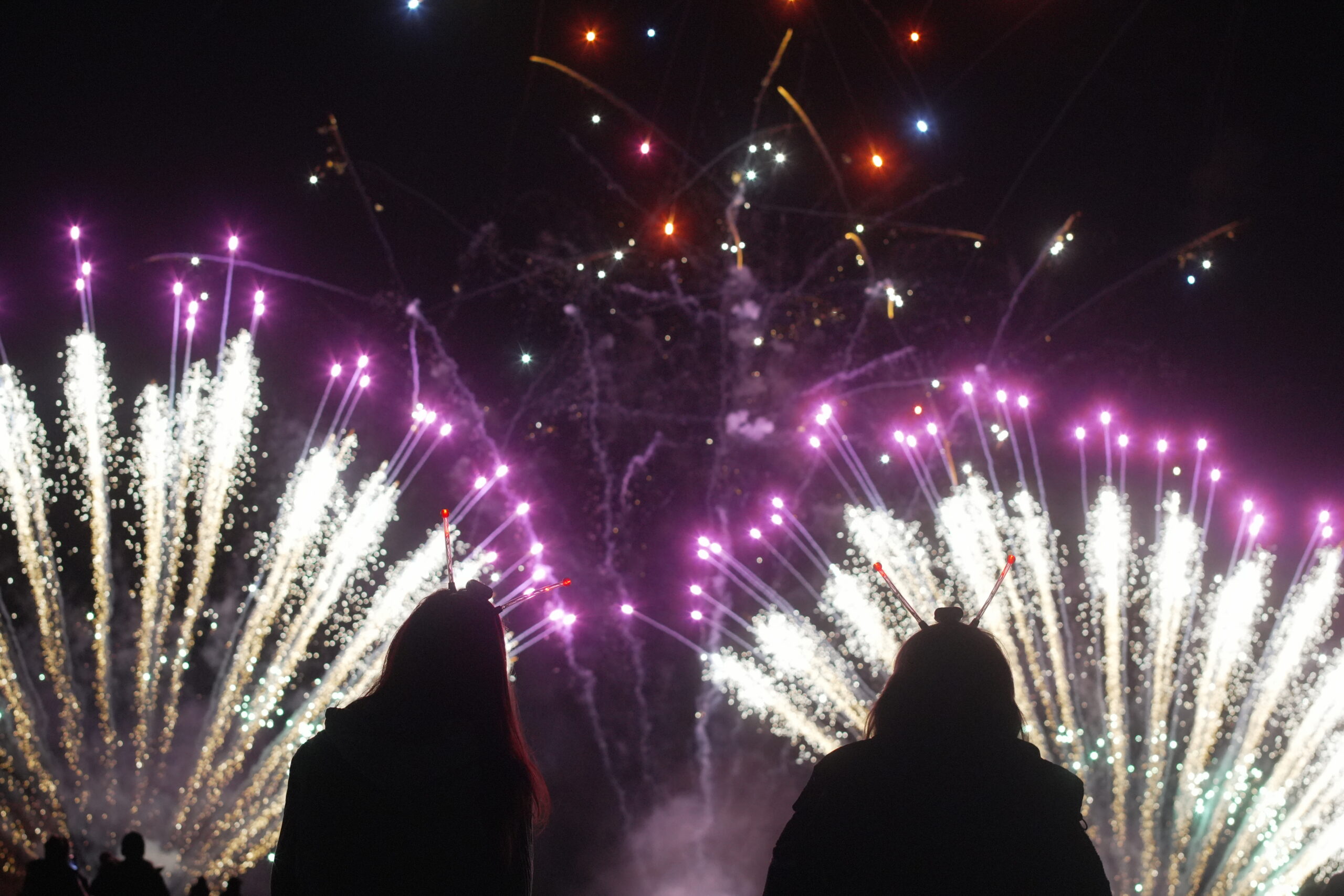 Silhouettes of people watching colourful fireworks bursting in the night sky at St Margaret’s Hospice Fireworks Night