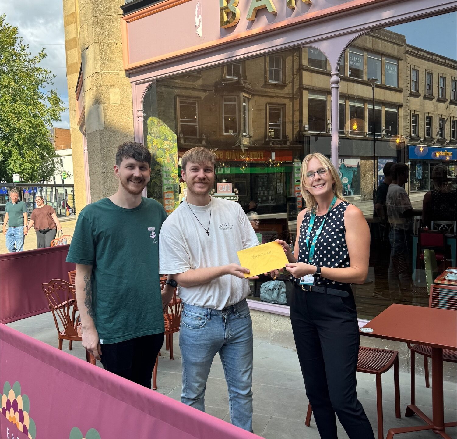 St Margaret's Hospice representative handing a golden envelope to two corporate partners to kick off the £50 fundraising challenge for businesses