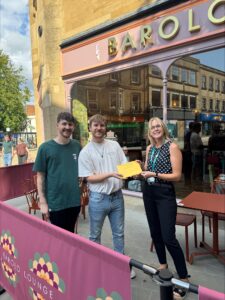 St Margaret's Hospice representative handing a golden envelope to two corporate partners to kick off the £50 fundraising challenge for businesses
